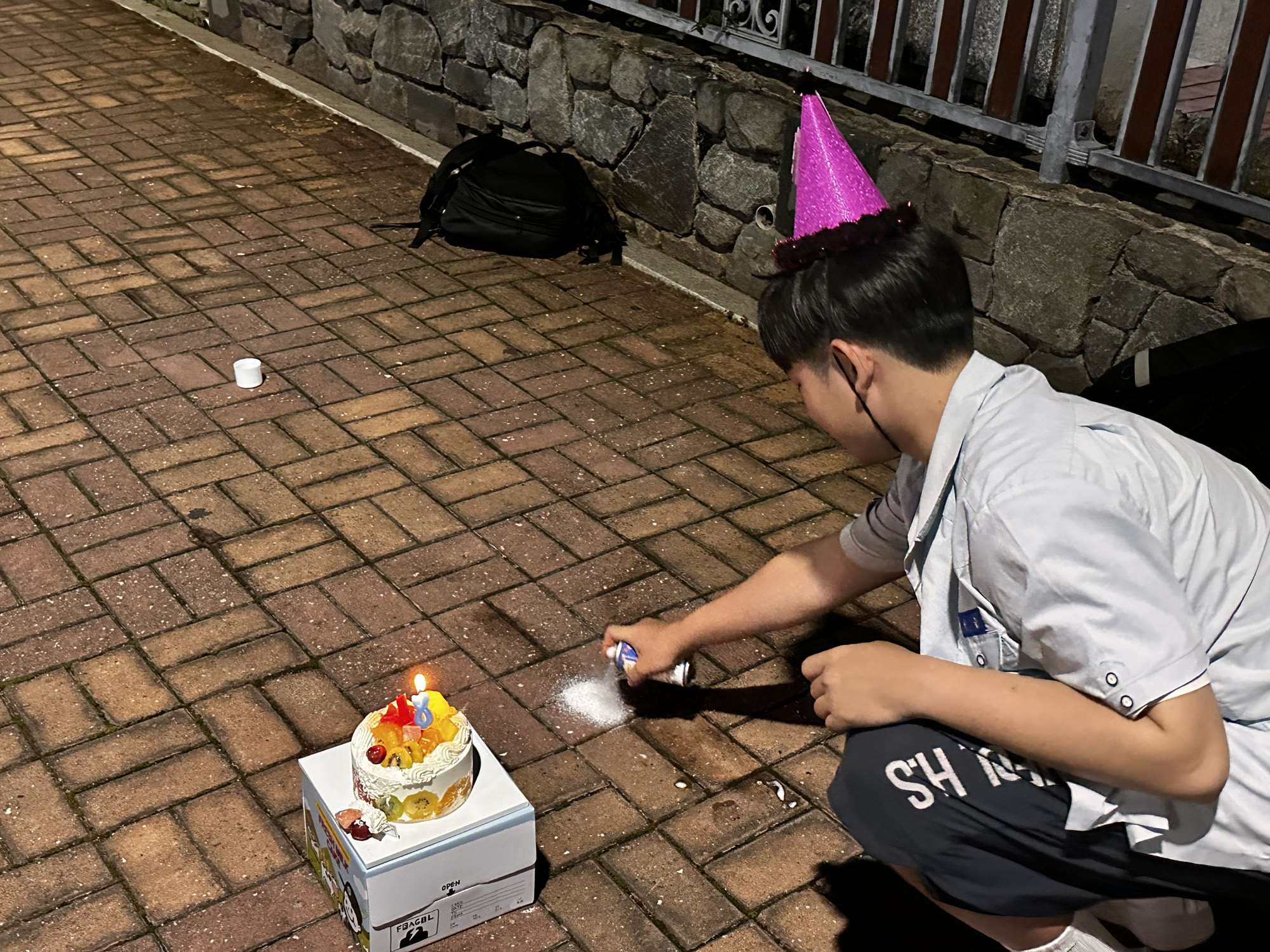 초 켜진 케이크 옆에서 스프레이를 뿌리는 모습